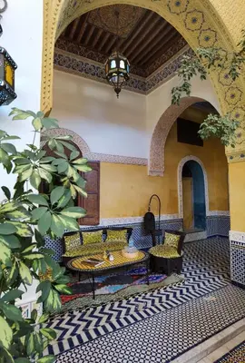a courtyard with a table and chairs in a building at Palais didi in Meknès