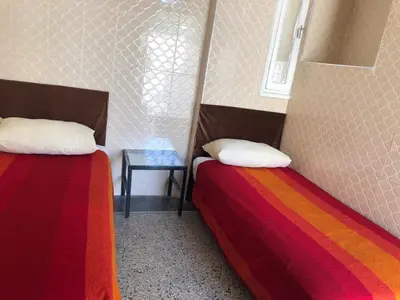 two beds in a room with a side table at Youth Hostel International Fez in Fès