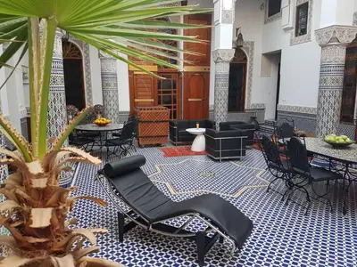 a lobby with black chairs and a palm tree at Riad Soleil d'Or in Fès