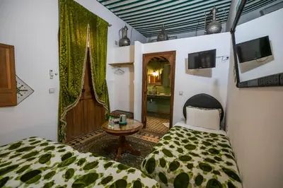 a bedroom with a bed and a table and a mirror at Riad Les Idrissides Chez LEA in Fès