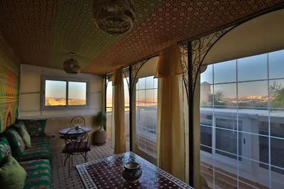 a living room with a couch and a table and windows at Riad Les Idrissides Chez LEA in Fès