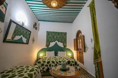 a bedroom with a bed and a table in a room at Riad Les Idrissides Chez LEA in Fès