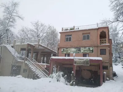 a building with snow on the ground next to it at Auberge Toubkal Amsouzart Aitst Idar in Tizgui