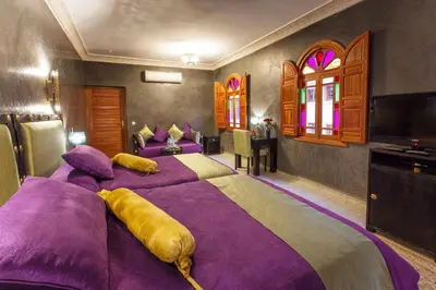 a bedroom with a large bed with purple and yellow pillows at Riad Andalib in Fès