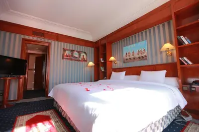 a bedroom with a large white bed and a television at Hotel Transatlantique in Meknès