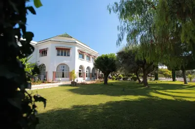 a large white house with trees in the yard at Hotel Transatlantique in Meknès