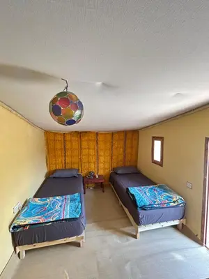 a bedroom with two beds and a chandelier at Auberge L'Oasis Mhamid in Mhamid
