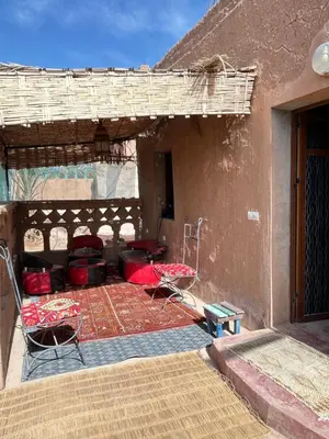 a patio with two chairs and a bed in a building at Auberge L'Oasis Mhamid in Mhamid