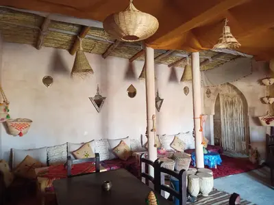 a room with a table and pillows on the wall at SaharaTime Camp in Hassilabied