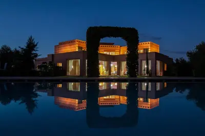 a house with a reflection in the water at night at Villa Koutoubia, jardin luxuriant, piscine et spa in Marrakech