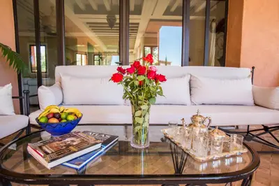 a living room with a white couch and a table with red flowers at Villa Koutoubia, jardin luxuriant, piscine et spa in Marrakech