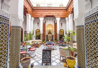 a lobby with tables and chairs in a building at Riad Dar Skalli & SPA in Fès