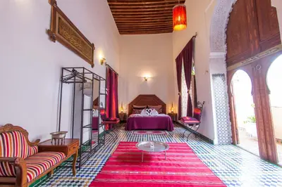 a bedroom with a bed and a red rug at Riad Dar Skalli & SPA in Fès