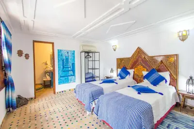a bedroom with two beds with blue pillows at Riad Dar Skalli & SPA in Fès