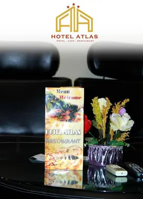 a table with a book and a vase with flowers at Hôtel Atlas Guercif in Guercif