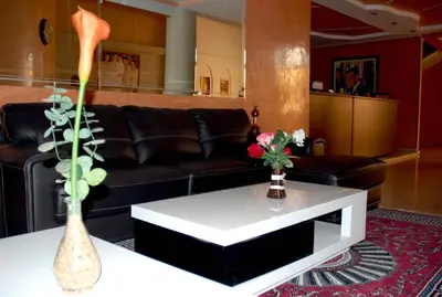a living room with a black couch and a white coffee table at Hôtel Atlas Guercif in Guercif