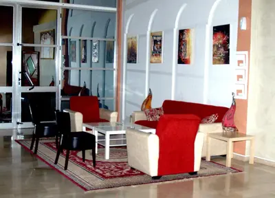 a living room with couches and a table and chairs at Hôtel Atlas Guercif in Guercif