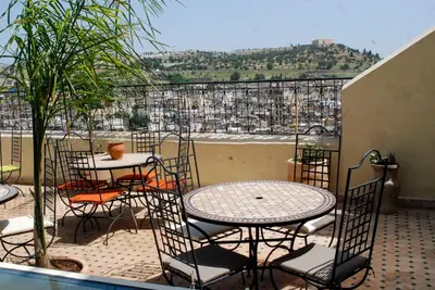 a patio with tables and chairs and a view of a city at Riad Le Patio De Fes in Fès