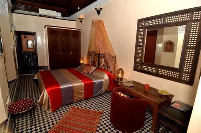 a bedroom with a bed and a table and a mirror at Riad Le Patio De Fes in Fès