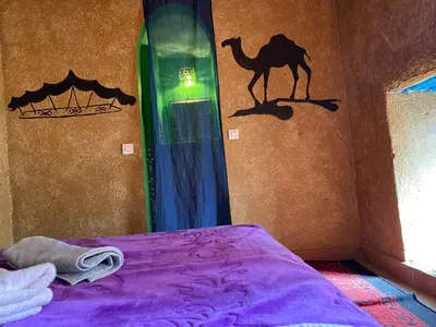 a bedroom with a bed with a painting of a camel on the wall at Dar Yaya in Mhamid