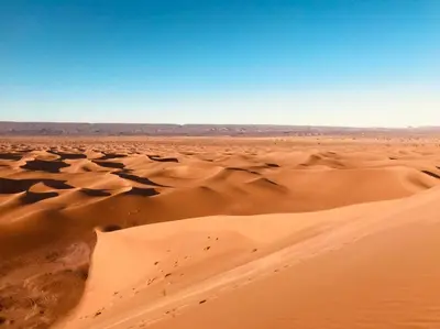a desert with sand dunes and a blue sky at Dar Yaya in Mhamid