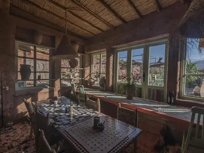 a dining room with a table and chairs and windows at Dar Tafantant in Marrakech