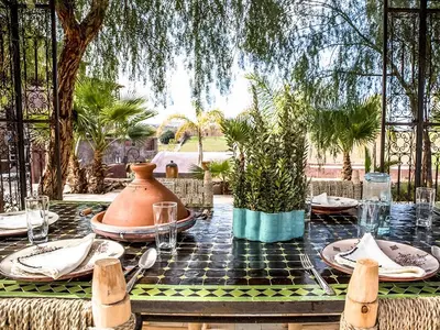 a table with a vase and plates on it at Dar Tafantant in Marrakech