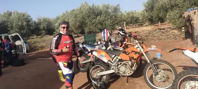 a man is standing next to a dirt bike at Dar Tadout in Aït Ourir
