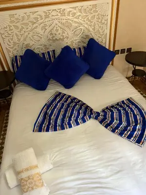 a bed with blue pillows and a bow tie on it at Riad Golf Stinia 1 in Meknès