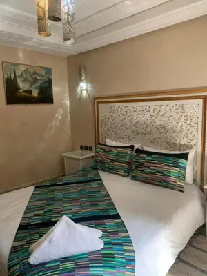 a bedroom with a large white bed with colorful pillows at Riad Golf Stinia 1 in Meknès