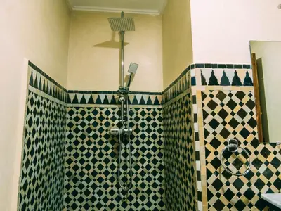 a bathroom with a shower with black and white tile at Riad Golf Stinia 1 in Meknès