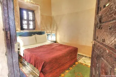a bedroom with a bed with a red blanket and a window at Kasbah Baha Baha in Nkob