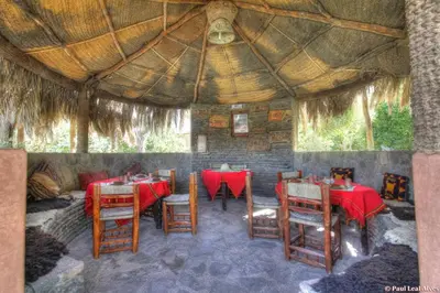 a restaurant with tables and chairs and a large umbrella at Kasbah Baha Baha in Nkob