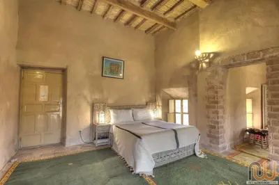 a bedroom with a bed in a stone wall at Kasbah Baha Baha in Nkob
