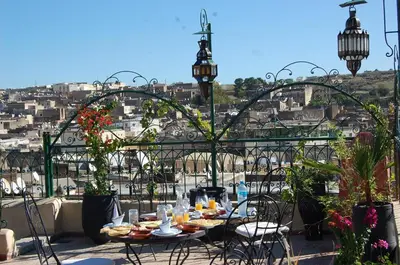 a table and chairs on a balcony with a view of a city at Riad Dar Guennoun - Luxury Suites in the Heart of Fes in Fès
