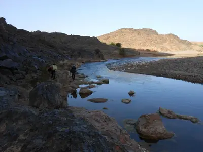 two people walking along a river in the desert at GITE D'etape SIDI FLAH in Sidi Flah
