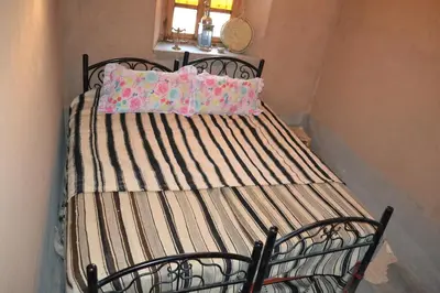 a metal bed with a striped blanket and two pillows at GITE D'etape SIDI FLAH in Sidi Flah