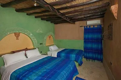 a bedroom with two beds with blue and green walls at Palmeras Y Dunas Luxery Camp in Merzouga