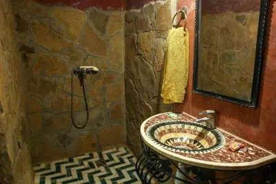 a stone bathroom with a sink and a shower at Palmeras Y Dunas Luxery Camp in Merzouga