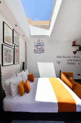 a bedroom with a large bed with orange and white pillows at Oscar Hotel by Atlas Studios in Ouarzazate