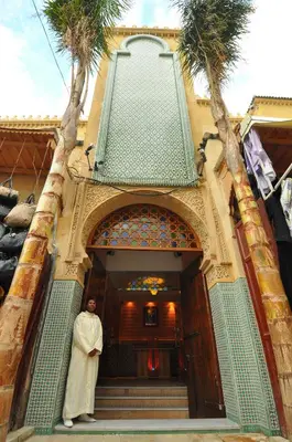 a man standing in front of a building with palm trees at Palais Riad Reda & Spa in Fès