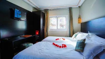 a bedroom with a white bed with red decorations on it at Palais Riad Reda & Spa in Fès