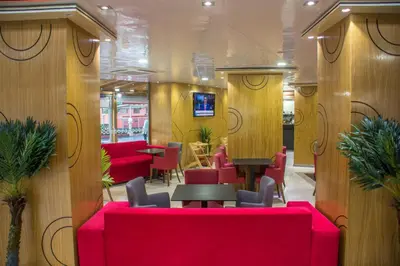 a restaurant with red couches and tables and chairs at Hôtel Hadaik Ain Asserdoune in Beni Mellal