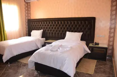 a hotel room with two beds with white sheets at Hôtel Hadaik Ain Asserdoune in Beni Mellal