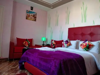 a bedroom with a red bed and a red couch at Hôtel Hadaik Ain Asserdoune in Beni Mellal