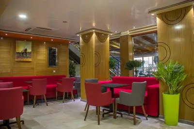 a restaurant with red tables and red chairs at Hôtel Hadaik Ain Asserdoune in Beni Mellal