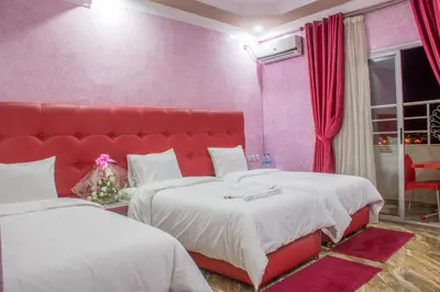 a bedroom with two beds and a large red headboard at Hôtel Hadaik Ain Asserdoune in Beni Mellal