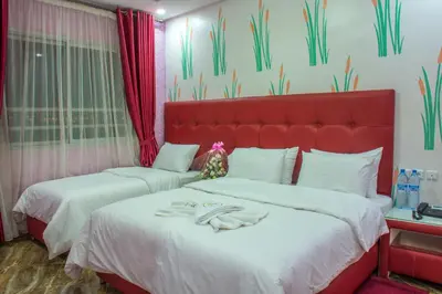 two beds in a room with a red headboard at Hôtel Hadaik Ain Asserdoune in Beni Mellal
