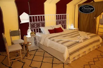 a bedroom with a large bed and a chair at Karim Sahara Prestige in Zagora