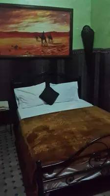 a bedroom with a bed with a painting on the wall at Riad Anass Al Ouali in Fès